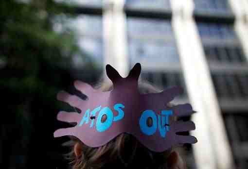 A protester wears an "Atos Out" sign during a demonstration at the Department of Work and Pensions. Photograph: Getty Images